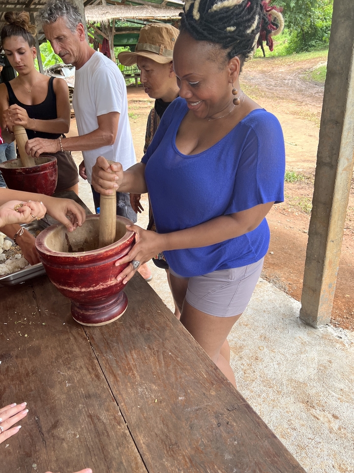 Des personnes utilisant un mortier et un pilon dans un cadre extérieur.