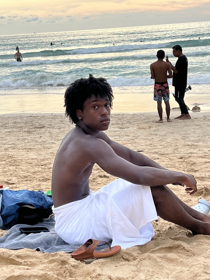 Une personne assise sur la plage regardant l'océan.