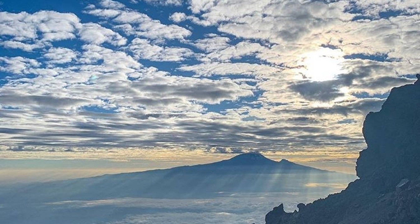 Vue dramatique d'une montagne avec le soleil qui brille à travers les nuages