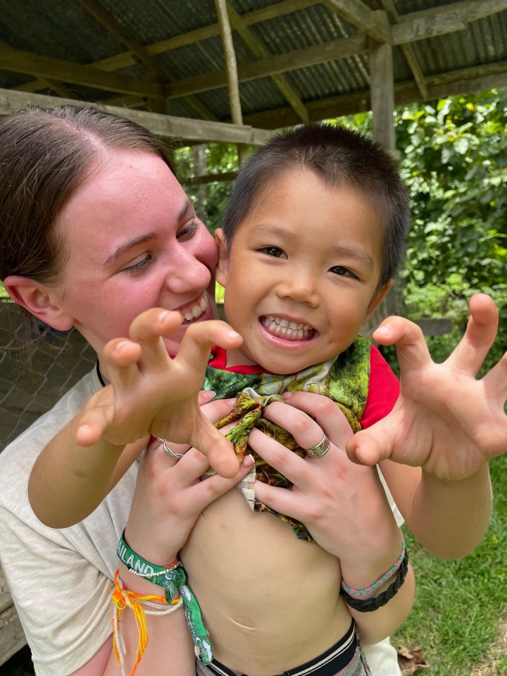 Young woman hugging and playfully interacting with a child.