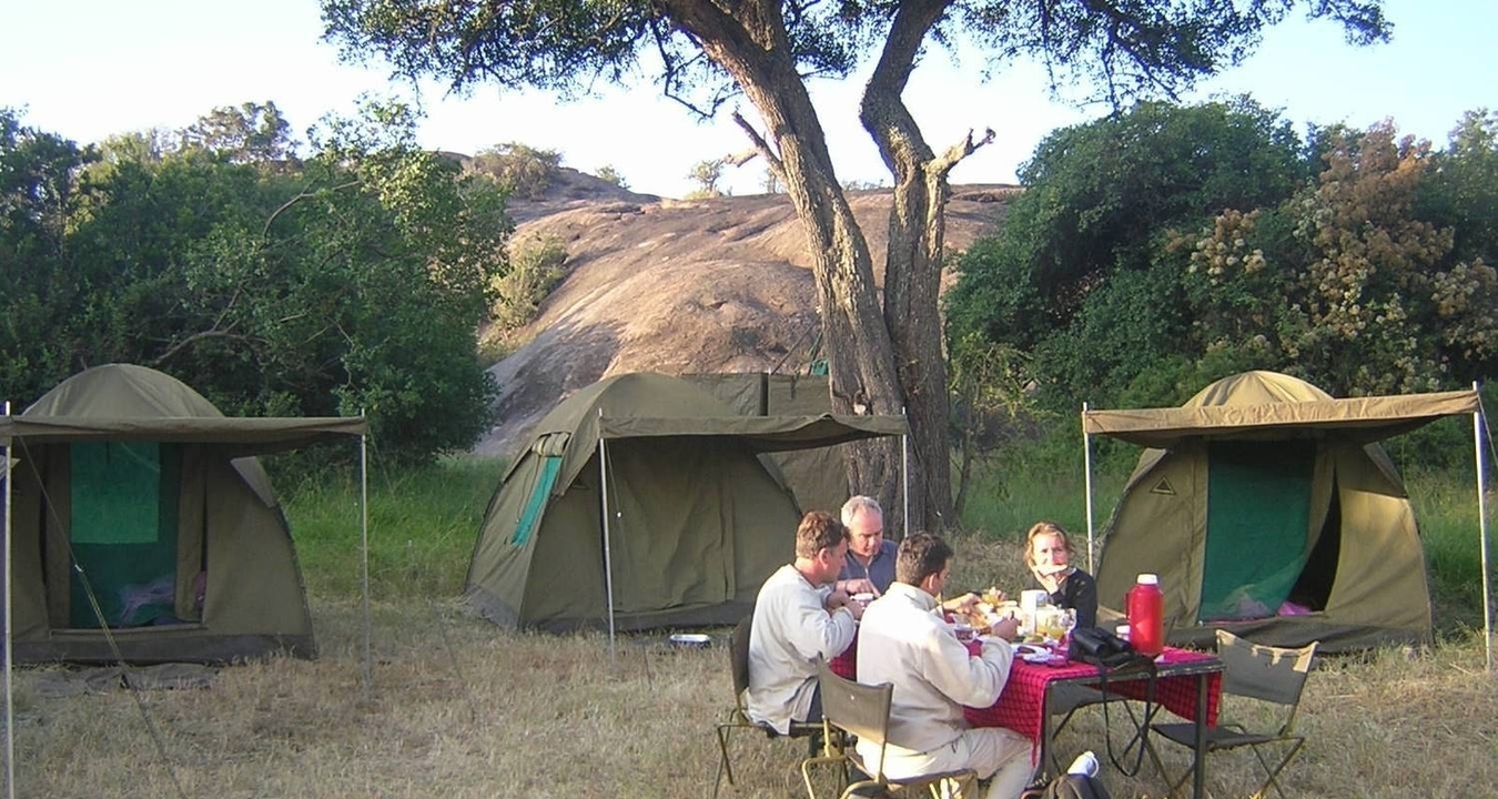 Les gens dînent dehors avec des tentes en arrière-plan
