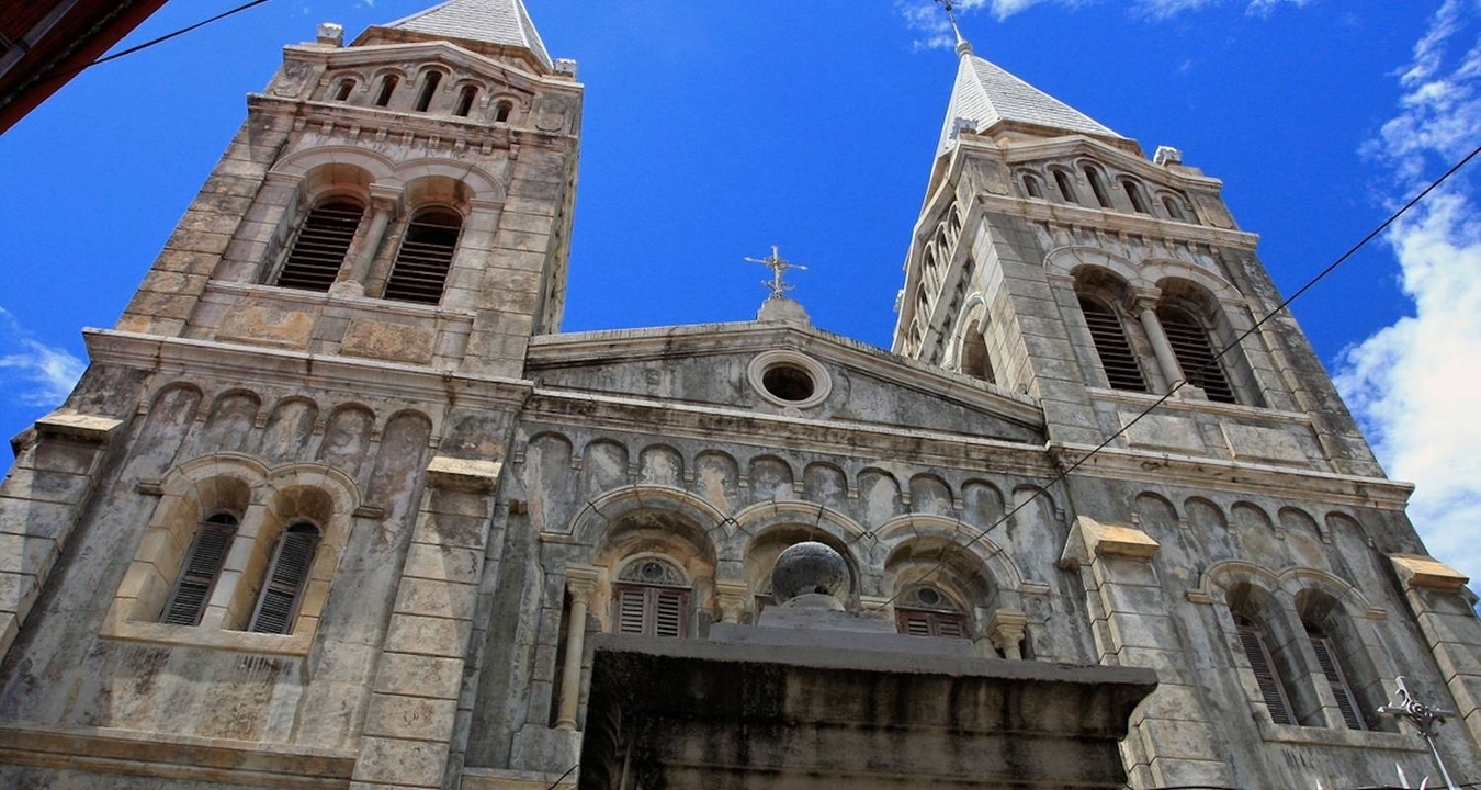 Vue d'une façade d'église en pierre ornée contre un ciel bleu.