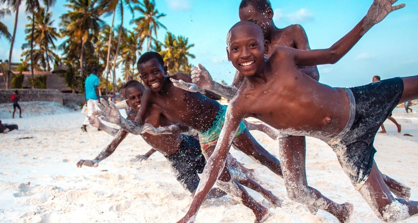 Des enfants qui jouent énergiquement sur une plage de sable.