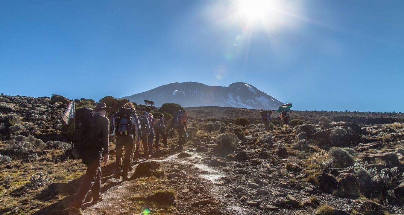 Des randonneurs sur un sentier rocheux sous un soleil éclatant.