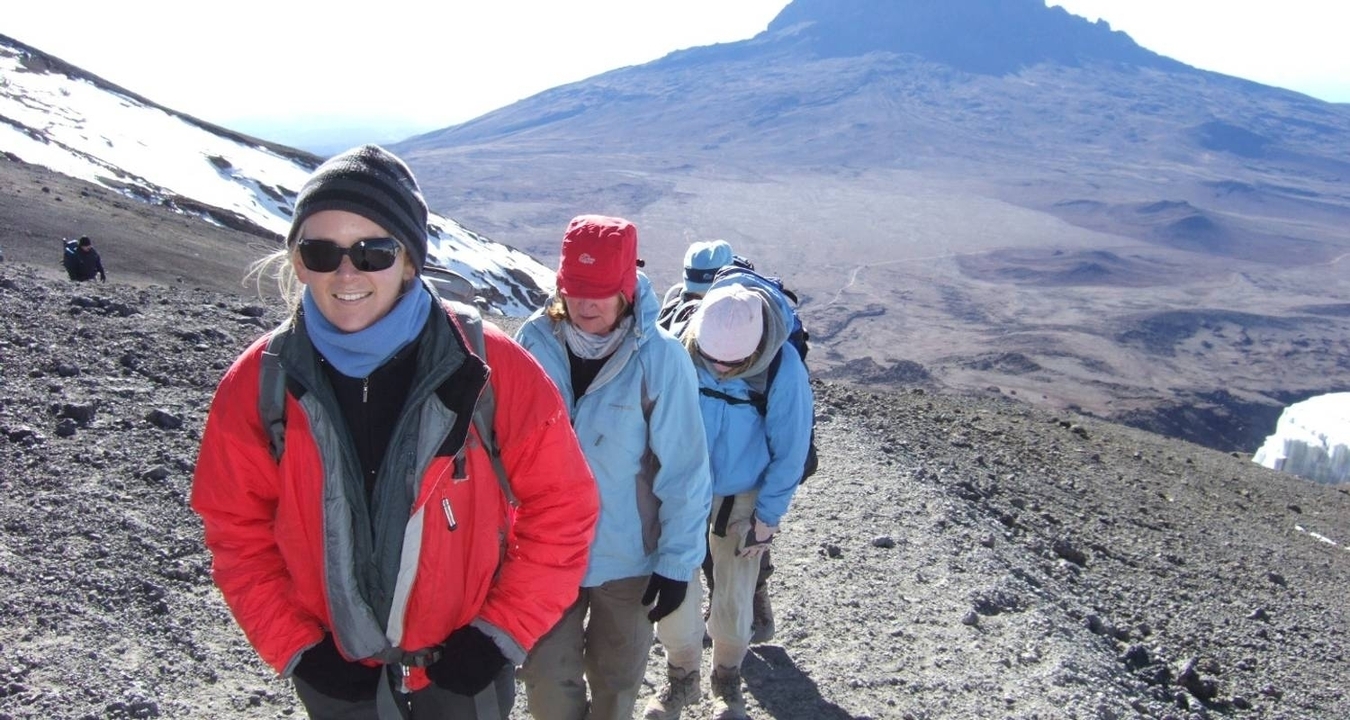 Randonneurs gravissant une pente aride avec le mont Kilimandjaro.