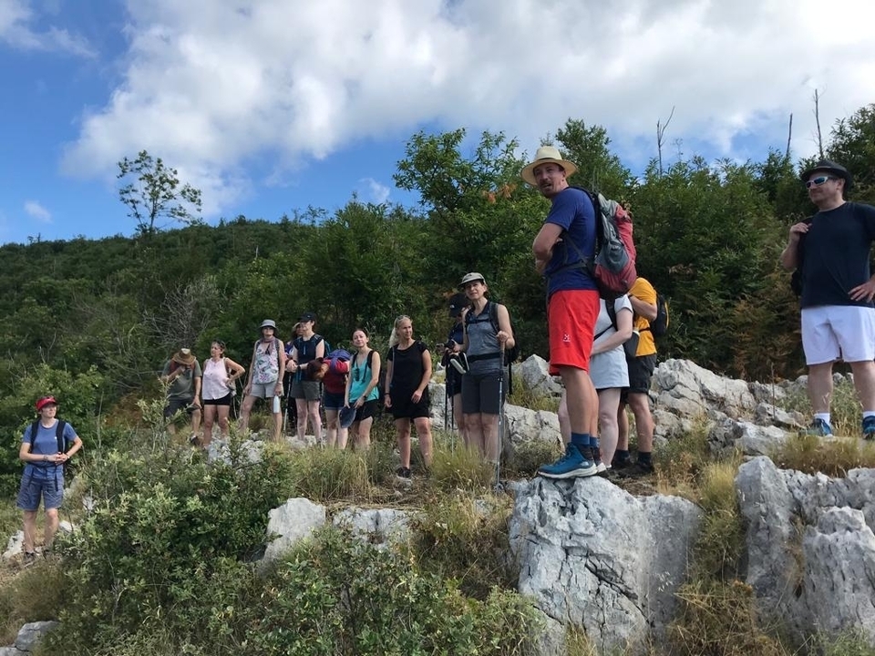 Groupe de randonneurs sur un sentier rocheux entouré d'arbres.