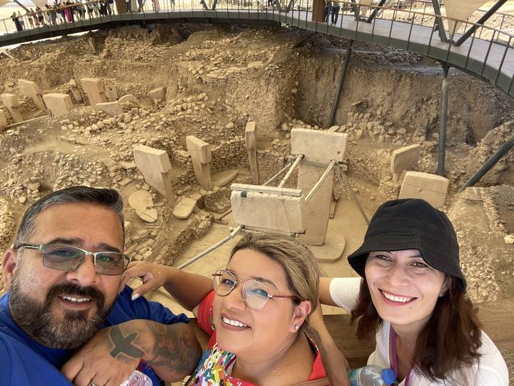 Trois personnes avec des structures de pierre anciennes en arrière-plan.