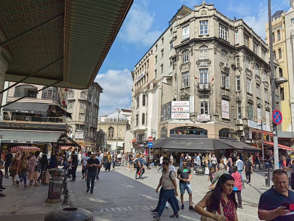 Rue animée avec des bâtiments historiques et des gens qui marchent.