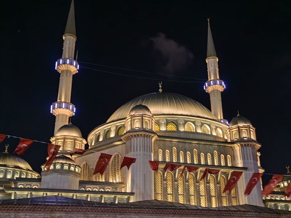 Mosquée illuminée avec minarets la nuit.