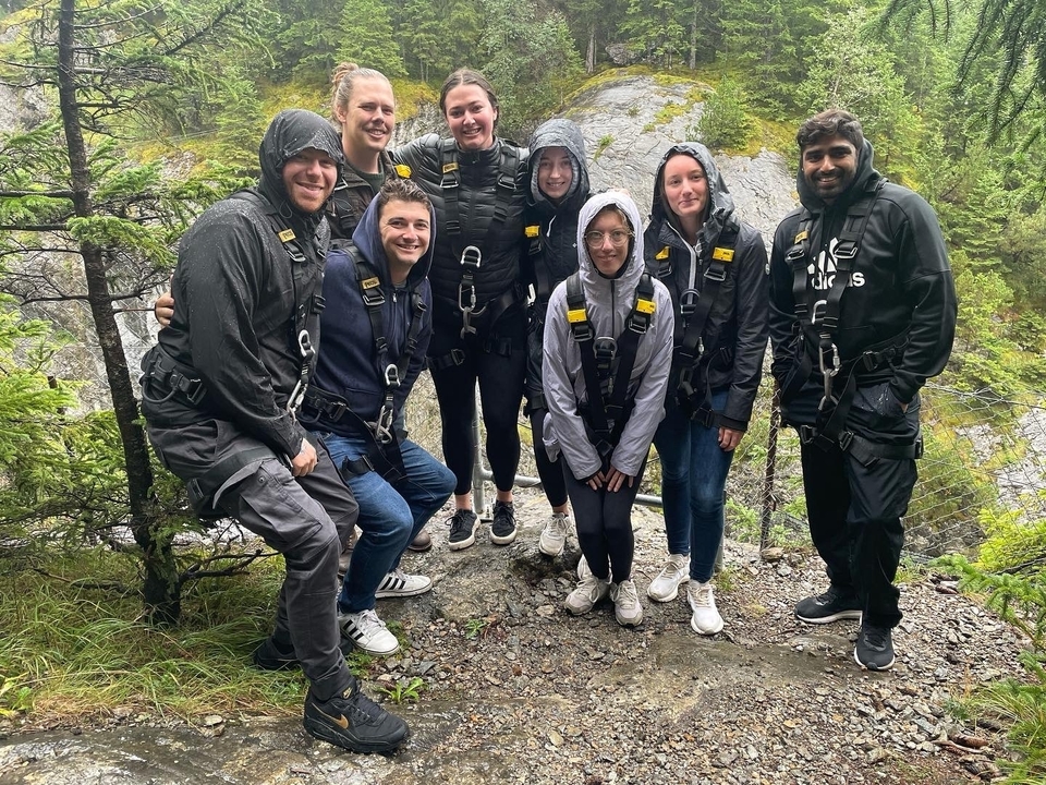Travelers wearing safety harnesses posing happily on a rainy forest trail