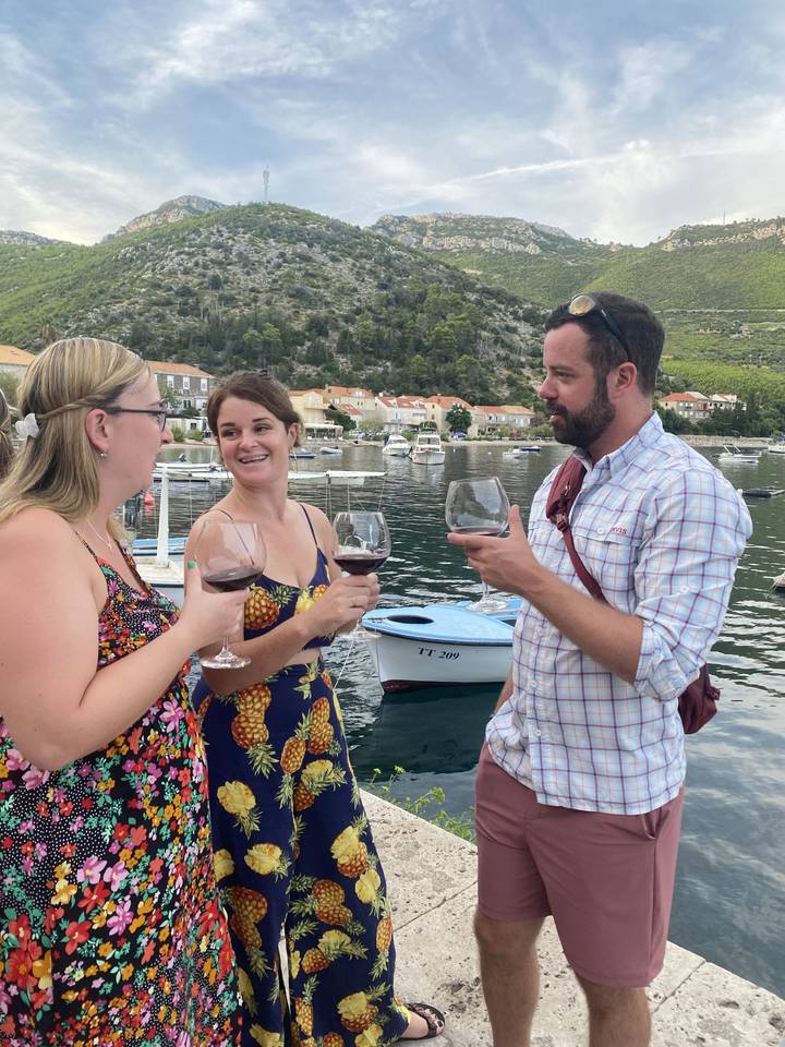 Groupe de personnes ayant une discussion avec des verres de vin au bord de l'eau.
