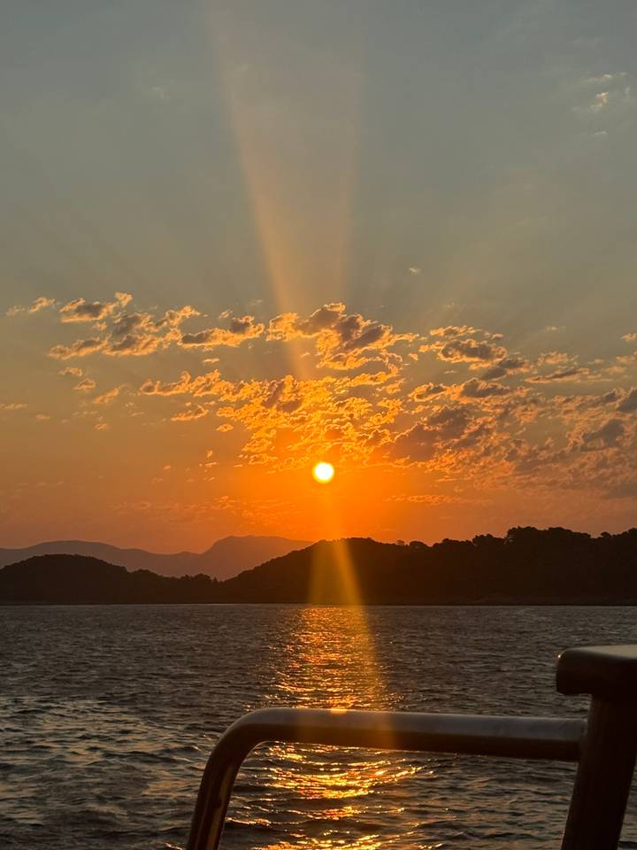 Sunset over the ocean with orange sky and clouds.