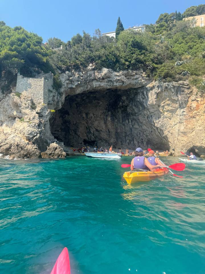 Kayak adventure near a cave with clear blue waters.