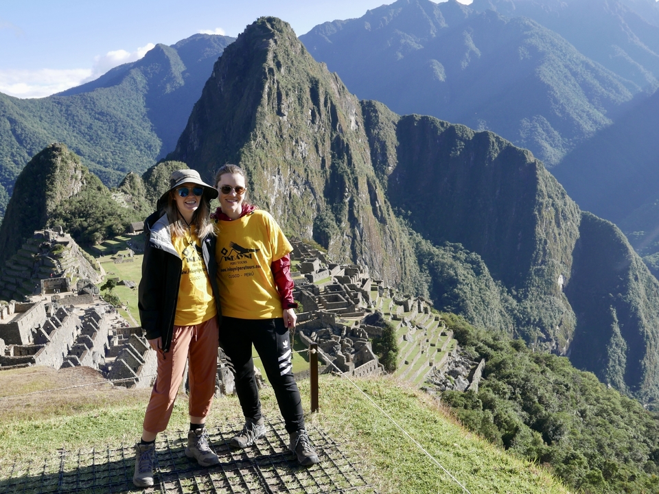 Deux personnes posant au Machu Picchu avec un magnifique paysage montagneux en arrière-plan.