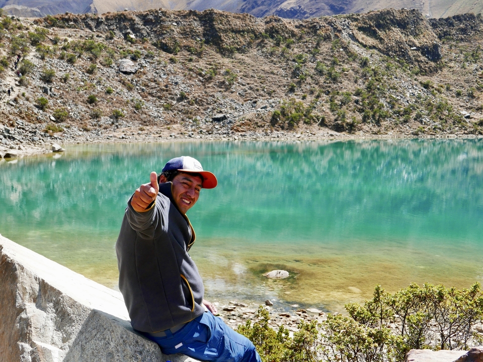 Un homme posant avec énergie au bord d'un lac turquoise.