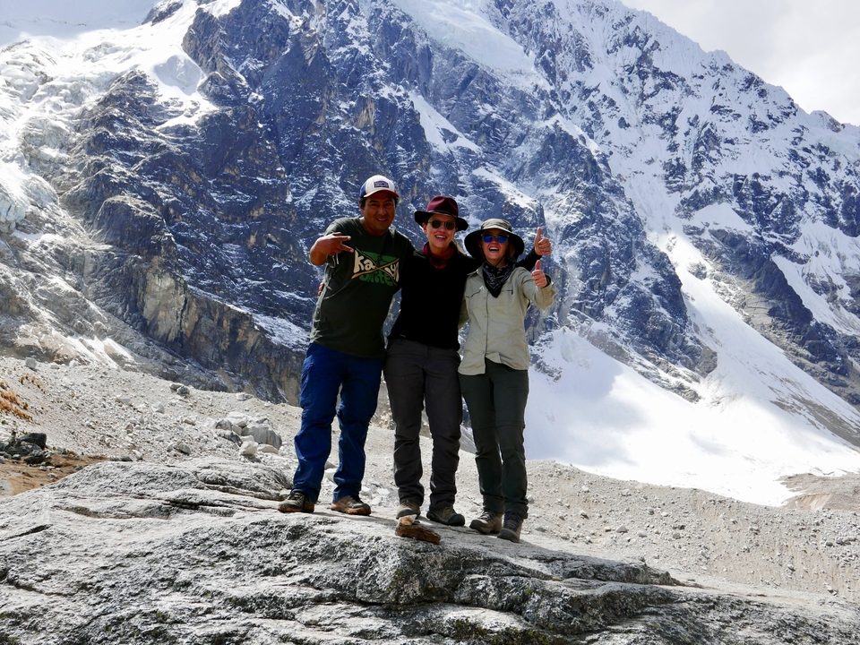 Trois randonneurs posant au pied d'une montagne enneigée.
