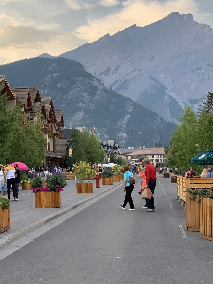 Rue animée avec des gens qui marchent, sur fond de montagne.