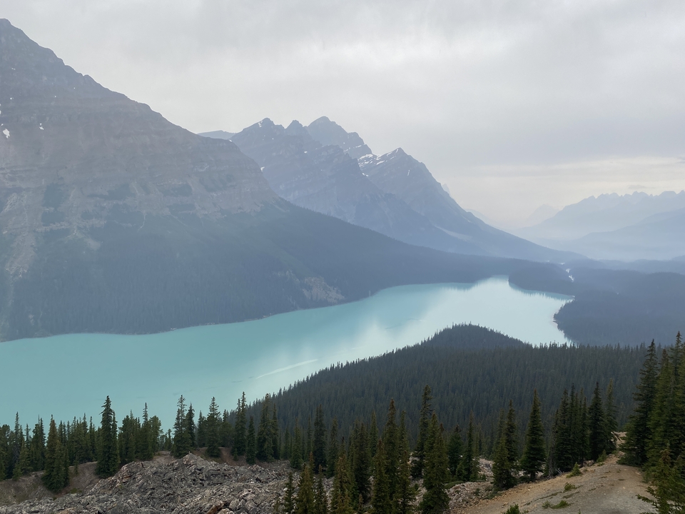 Vue panoramique d'un lac turquoise dans une vallée entourée de montagnes.
