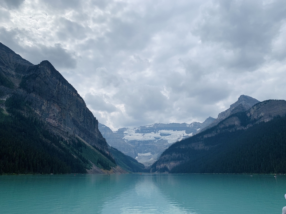 Lac entouré de montagnes escarpées et de ciel nuageux.