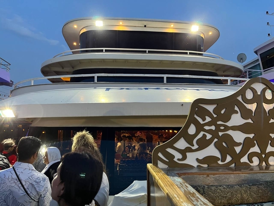 Des personnes rassemblées près d'un bateau pendant la nuit avec des éléments décoratifs.