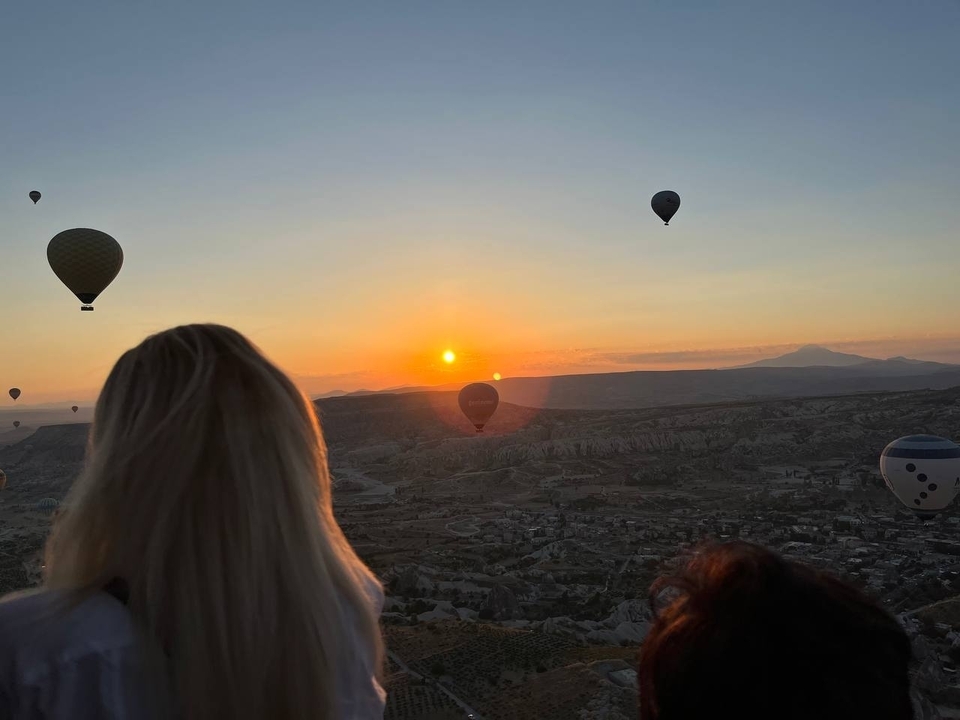 Montgolfières flottant dans le ciel au lever du soleil avec un paysage en contrebas.