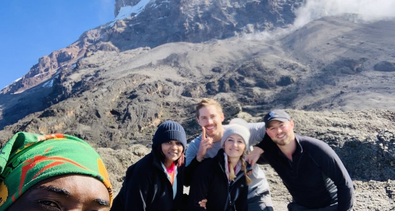Groupe de personnes posant avec le mont Kilimandjaro en arrière-plan.