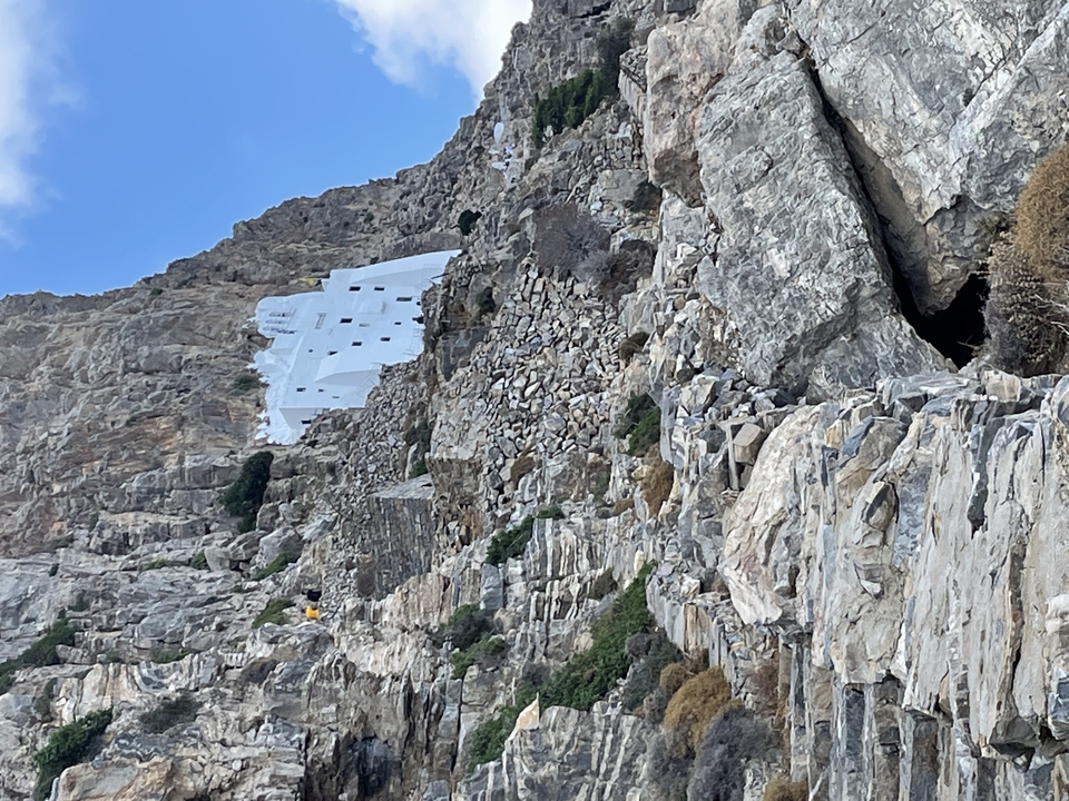 Steep rocky cliffside with a white building.