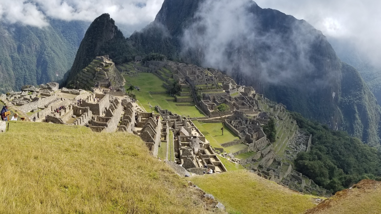 Ruines emblématiques du Machu Picchu entourées de montagnes couvertes de brume.