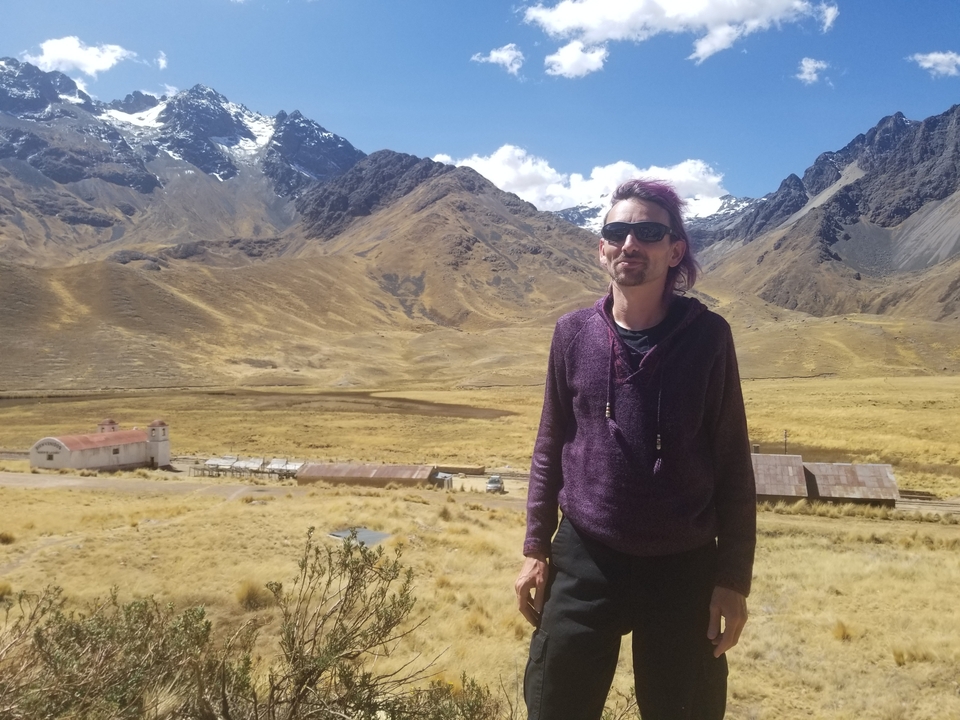 Homme debout devant un paysage montagneux avec un petit village.