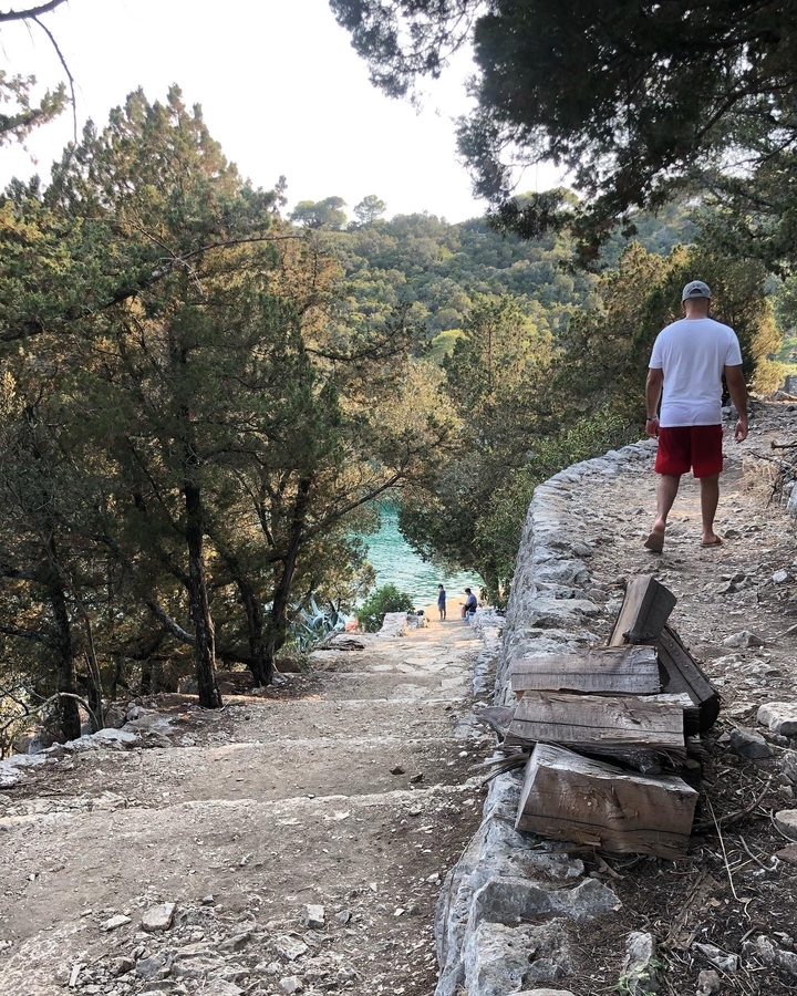 Sentier qui descend vers l'eau avec des gens qui marchent.