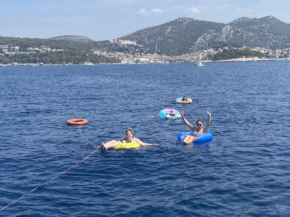 Des gens se détendent sur des matelas gonflables dans la mer avec une ville côtière en arrière-plan.