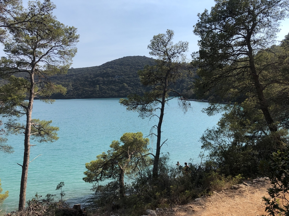 Vue panoramique d'un lac bleu entouré d'arbres et de collines.