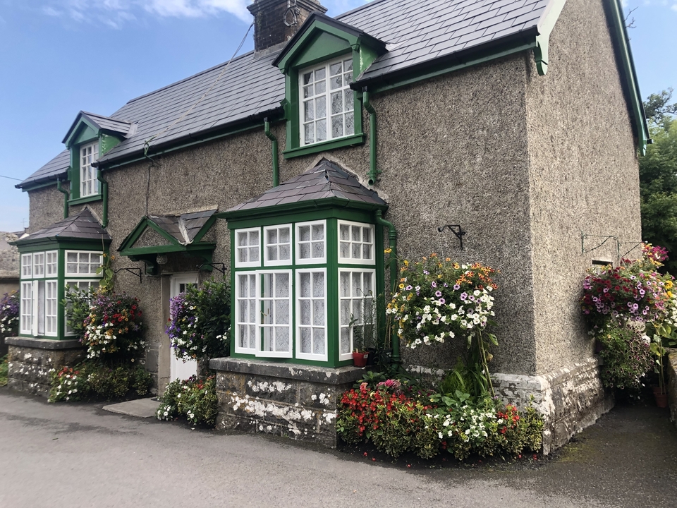Maison traditionnelle en pierre avec des fleurs colorées.