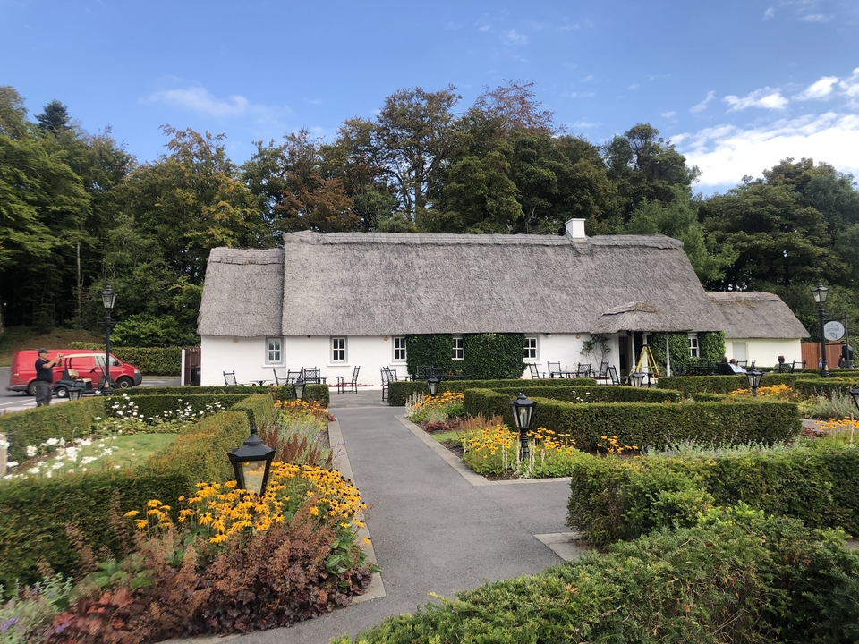 Chaumière au toit de chaume entourée de jardins.