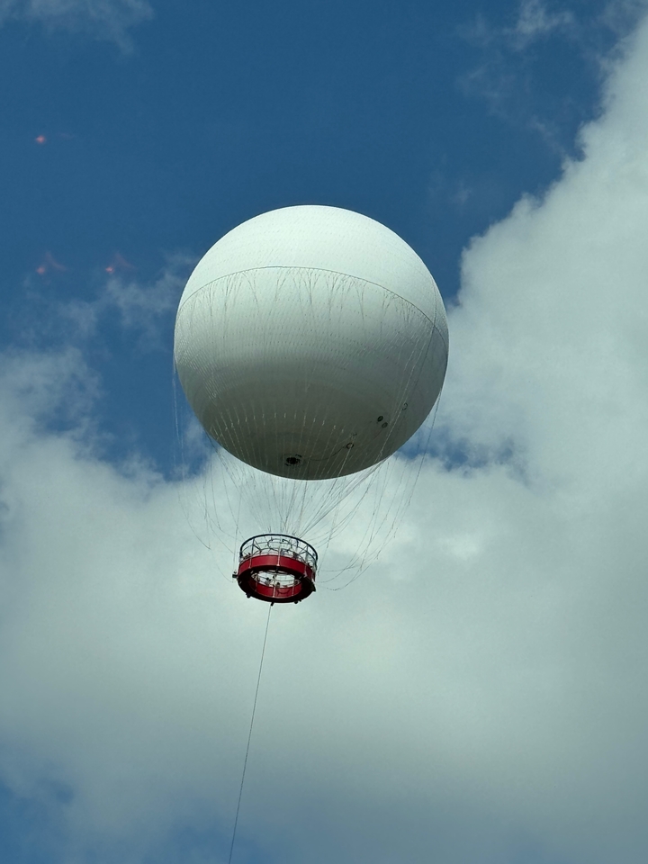 Ballon sphérique blanc attaché avec une nacelle en dessous.