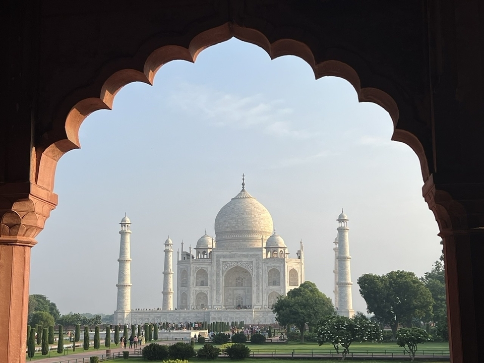 Le Taj Mahal vu à travers une porte voûtée ornementée.