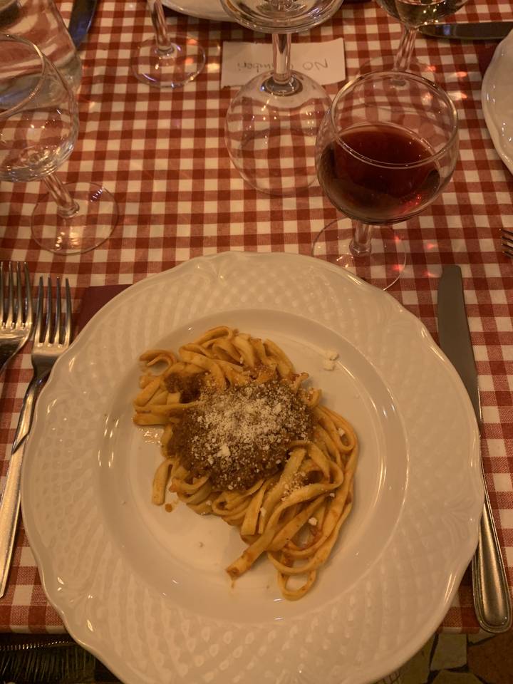 Plat de pâtes sur une nappe à carreaux avec du vin.