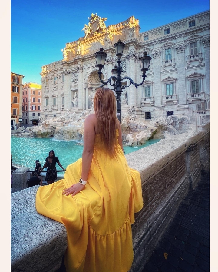Femme en robe jaune de dos à la fontaine de Trevi.