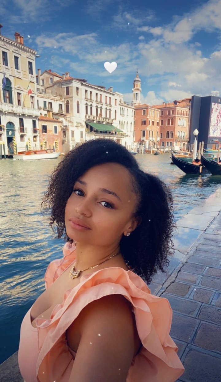 Femme près d'un canal à Venise avec des gondoles en arrière-plan.