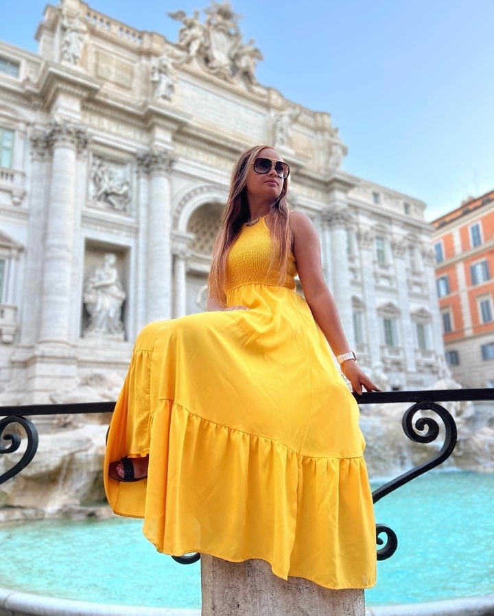 Femme en robe jaune assise près de la fontaine de Trevi.