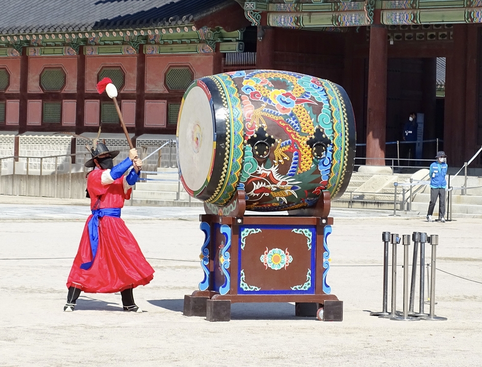 Tambour traditionnel coréen joué par un interprète en tenue colorée.