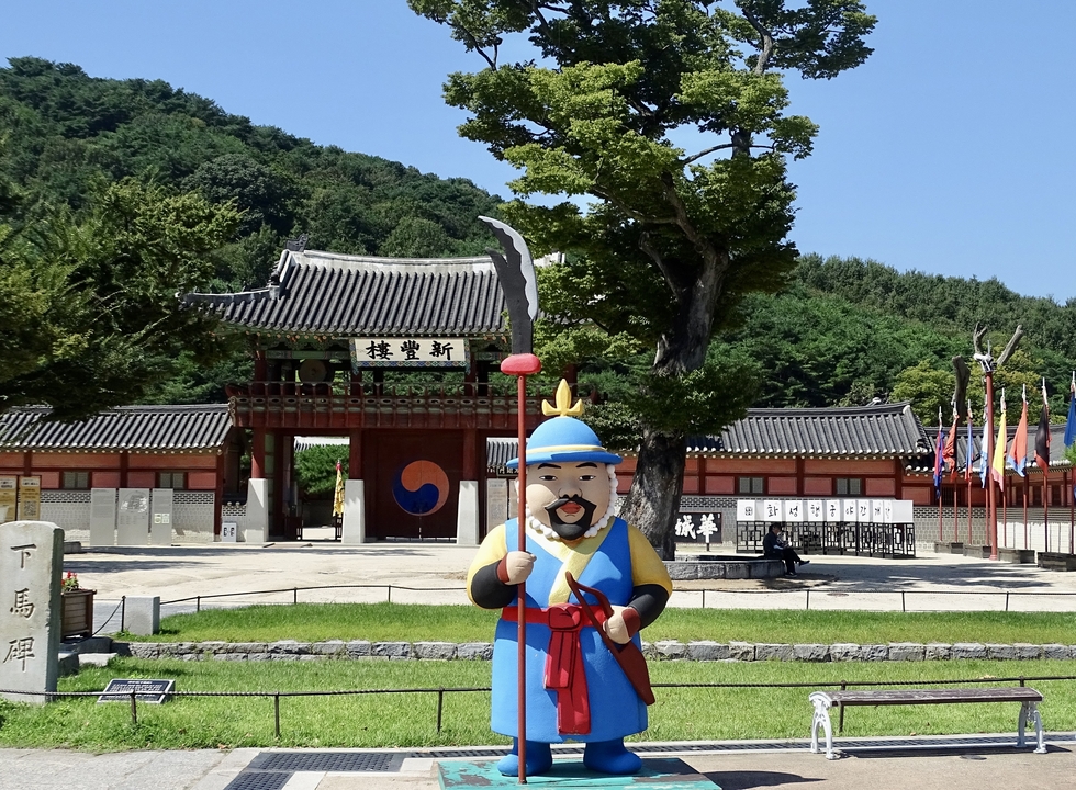 Statue d'un garde devant une porte d'entrée coréenne traditionnelle.