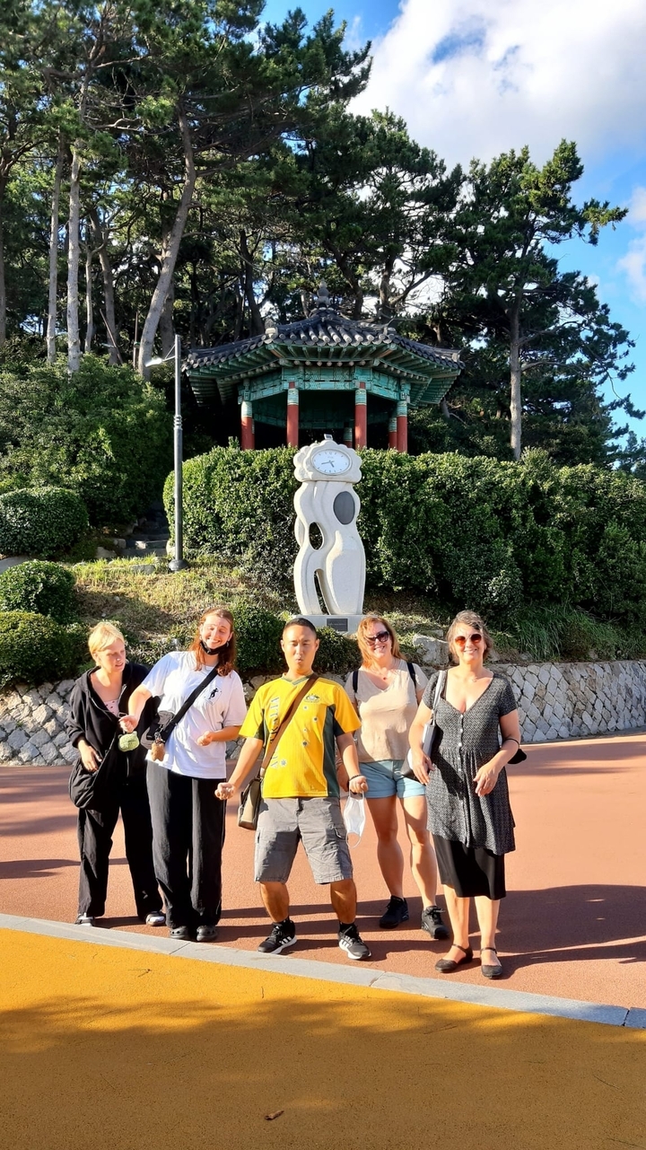 Groupe de personnes posant devant une sculpture d'horloge.