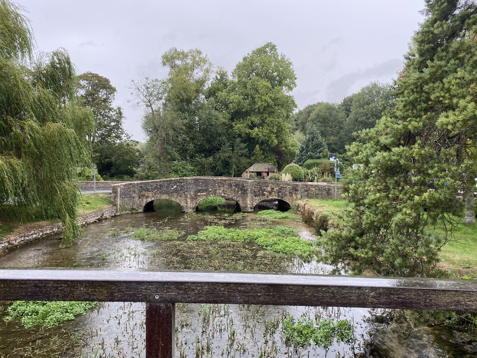 Pont de pierre sur une petite rivière avec un environnement verdoyant.