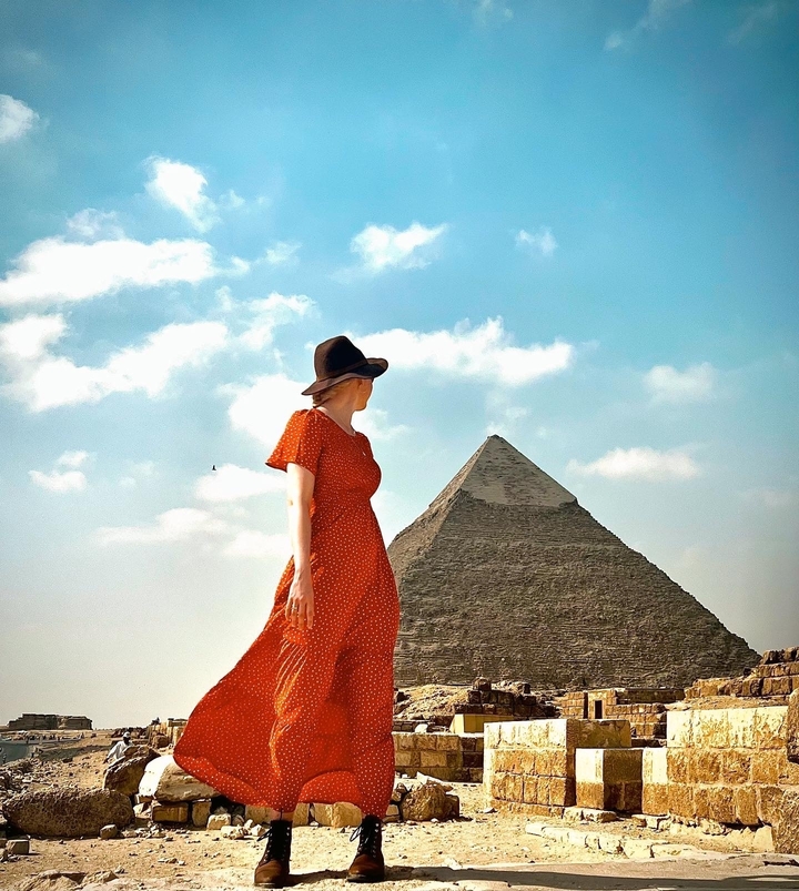 Personne en robe regardant une pyramide.