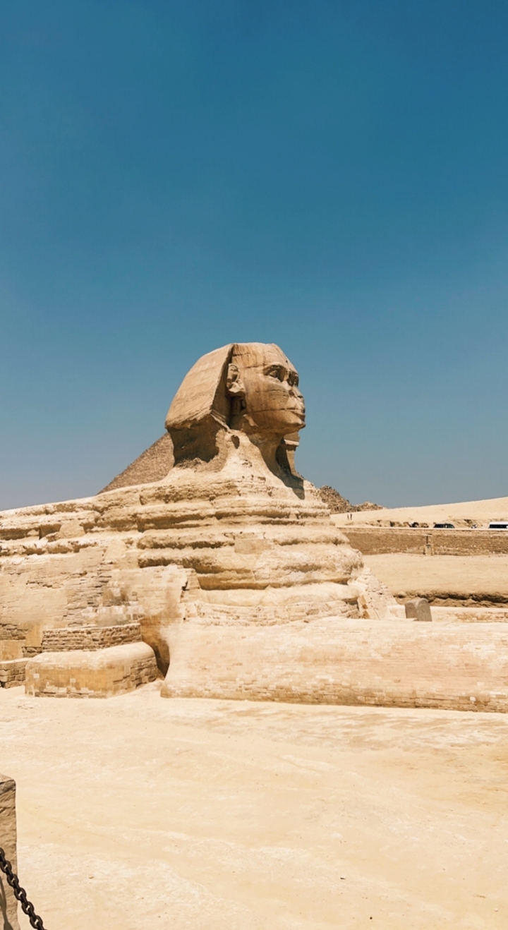 Statue de sphinx dans un décor désertique sous un ciel dégagé.