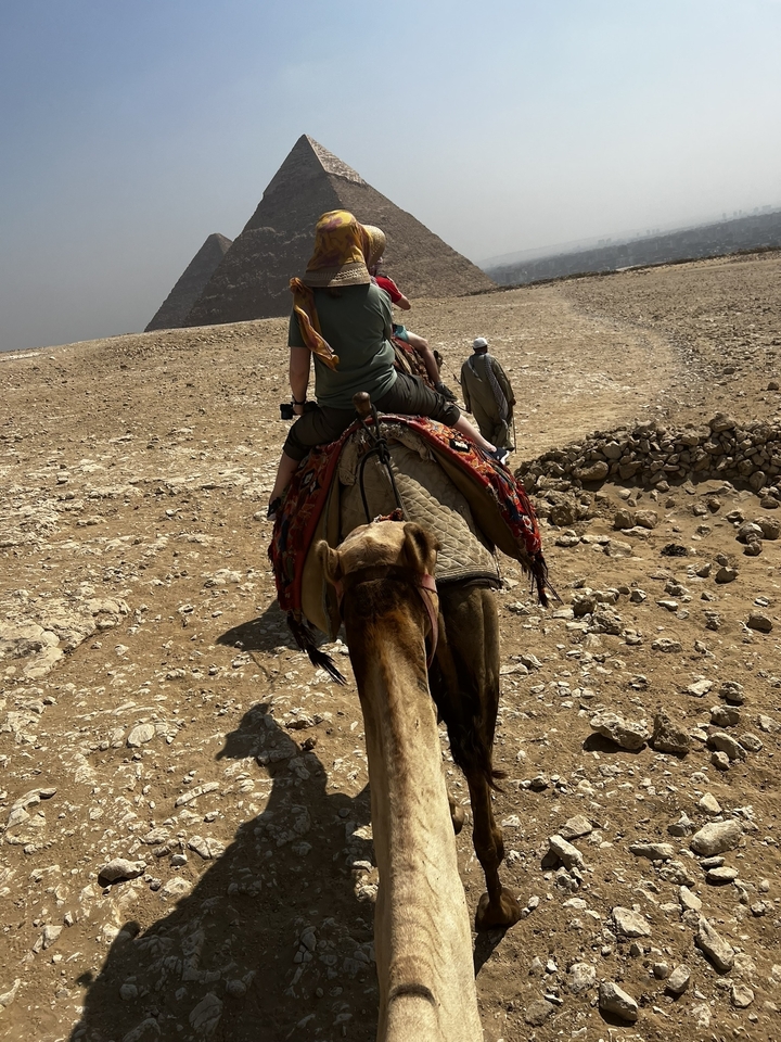 Promenade à dos de chameau dans le désert, des gens sur des chameaux avec un paysage rocheux.