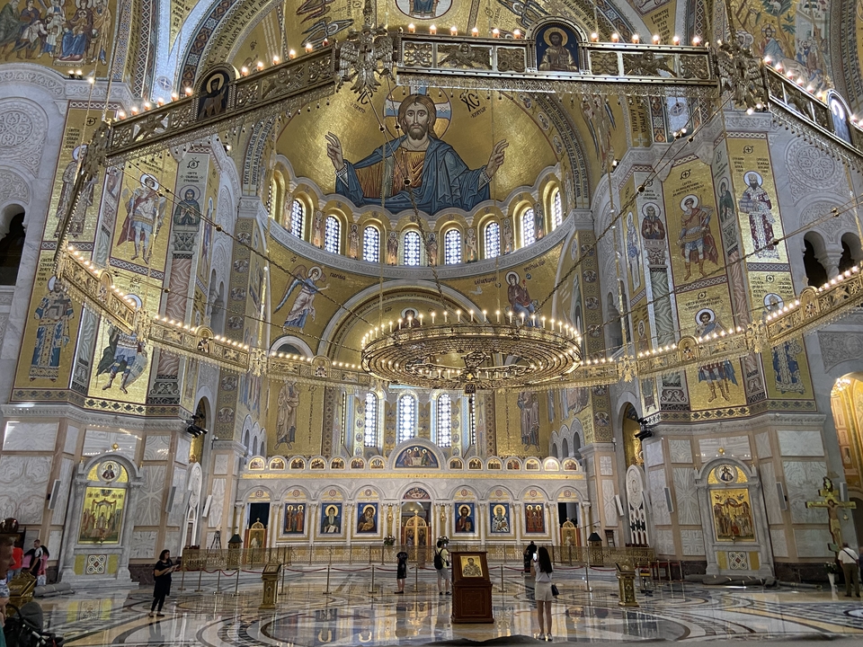 Innenraum einer prächtigen Kirche mit goldenen Mosaiken und Kronleuchtern.