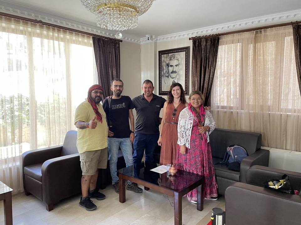 Cinq personnes posant dans une pièce avec de grandes fenêtres et un portrait.