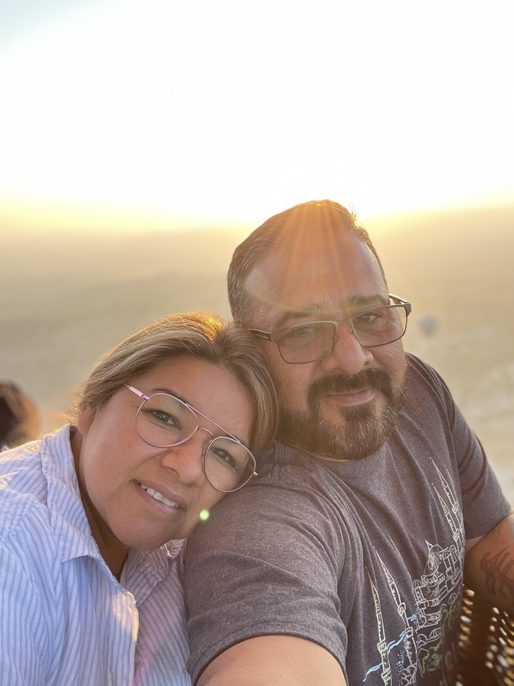 Couple posant avec un coucher de soleil en arrière-plan.